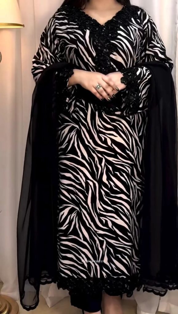 Woman wearing a luxury black and white zebra print suit set with detailed black lace neckline and sheer dupatta.